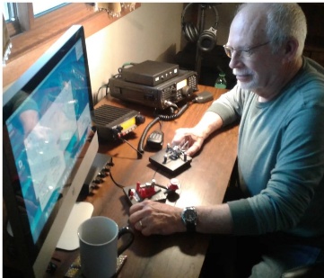 Amateur radio operator at home shack with Morse key and radio equipment